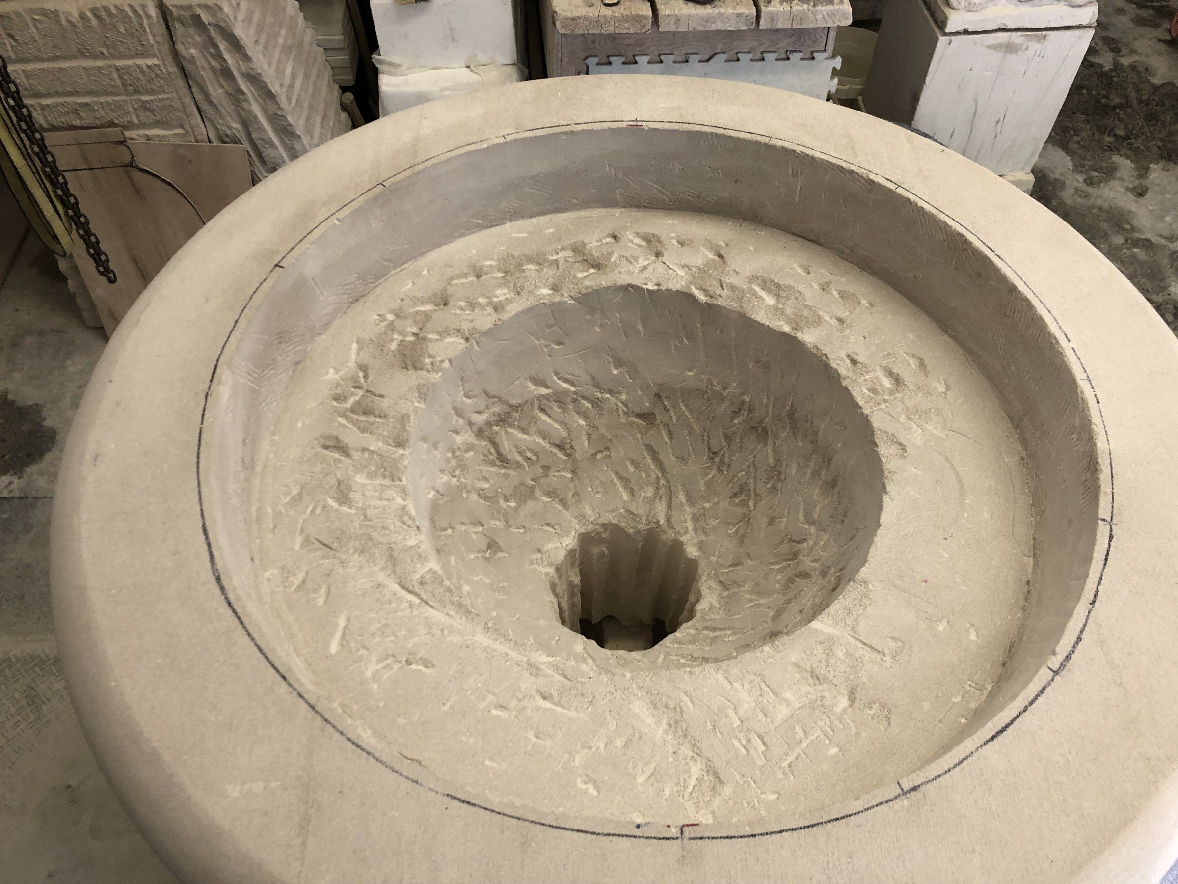 Looking down into the fire pit: the interior hollowed in stages, still rough with chisel marks around a deeper central opening, inside a pencilled outer rim.