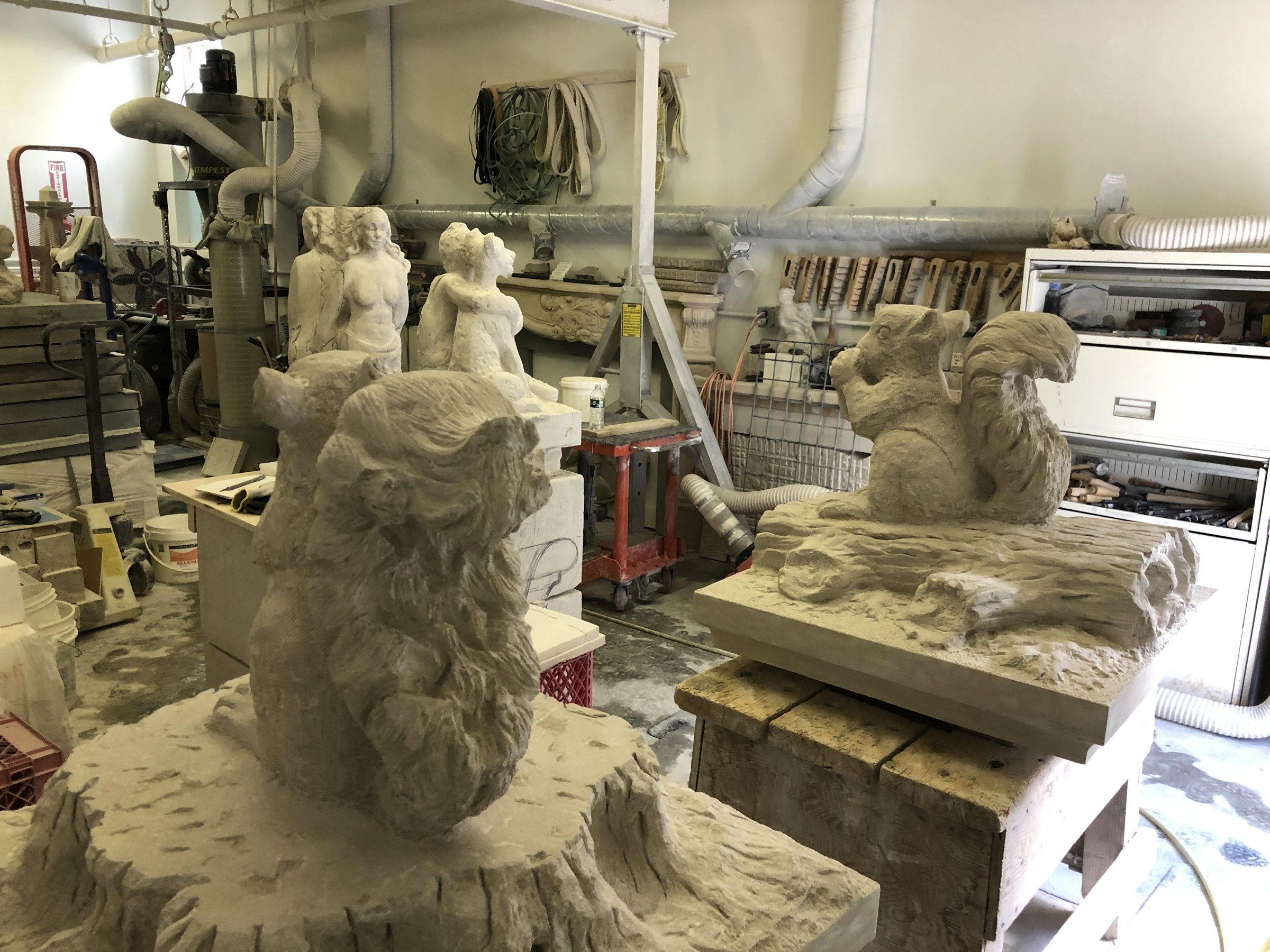 The two squirrels nearly finished in the studio, the one on the stump in the foreground and the one on the log on its bench to the right.