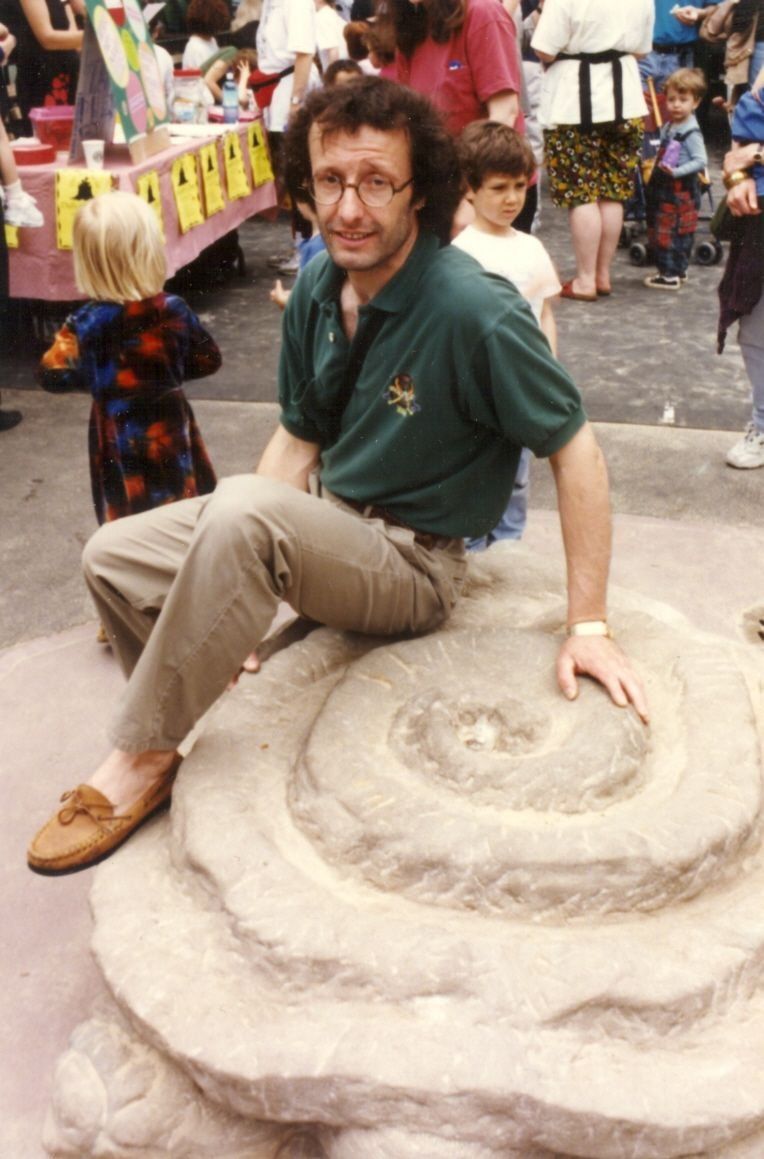 Jean-Claude Marchionni seated on the finished turtle at an outdoor gathering, with children and visitors around him.