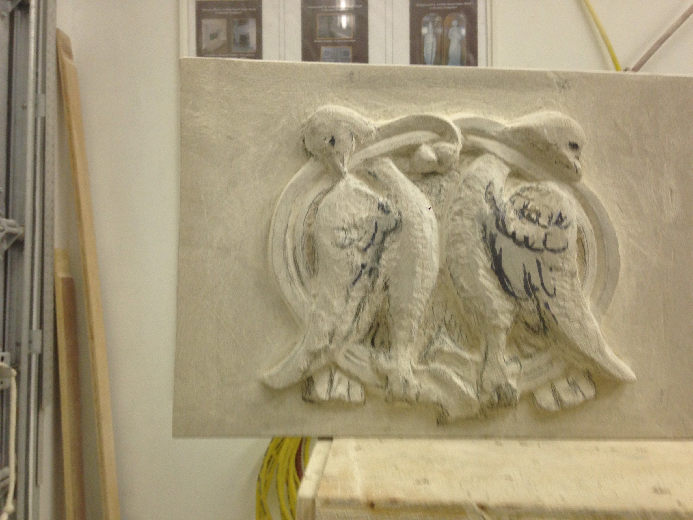 The bird relief seen straight on in the studio, the feathers being cut.