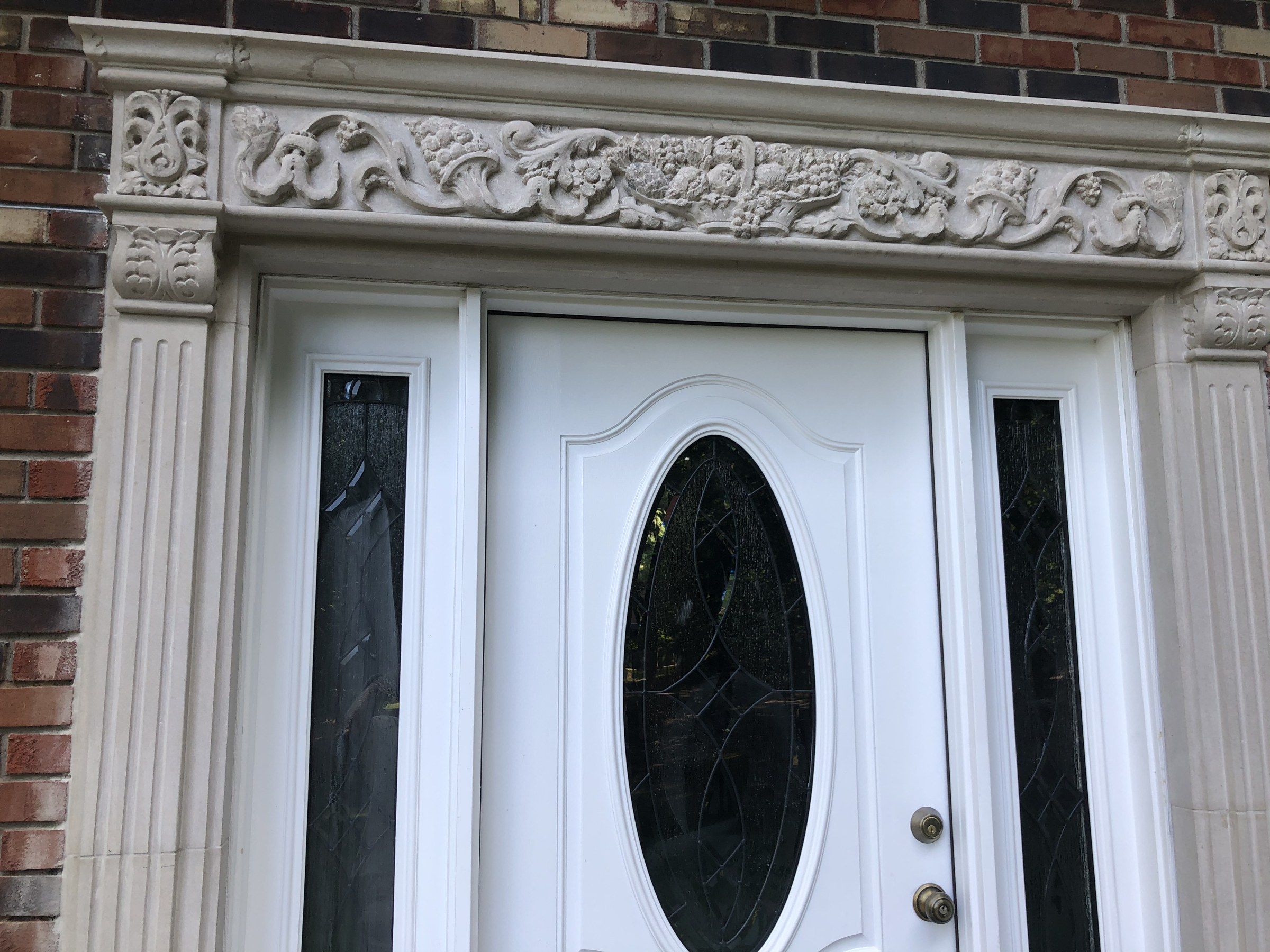 Close view of the frieze above the door: scrolling foliage, flowers and fruit between carved corner blocks.