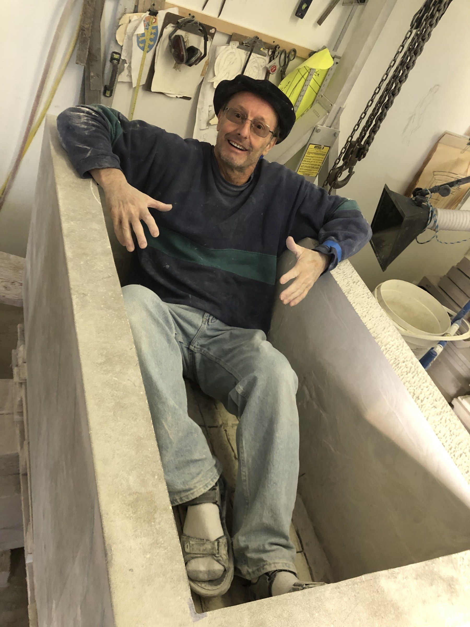 Jean-Claude Marchionni sitting inside the hollowed planter in the studio, smiling, arms open.