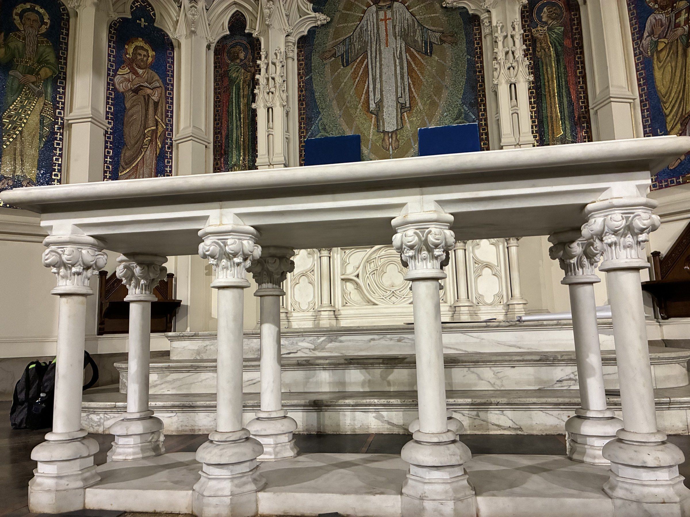 The communion table installed at the Lutheran church in New York City, viewed from the front — the white marble table with its slender colonnettes set before the gothic reredos and the great mosaic of Christ.