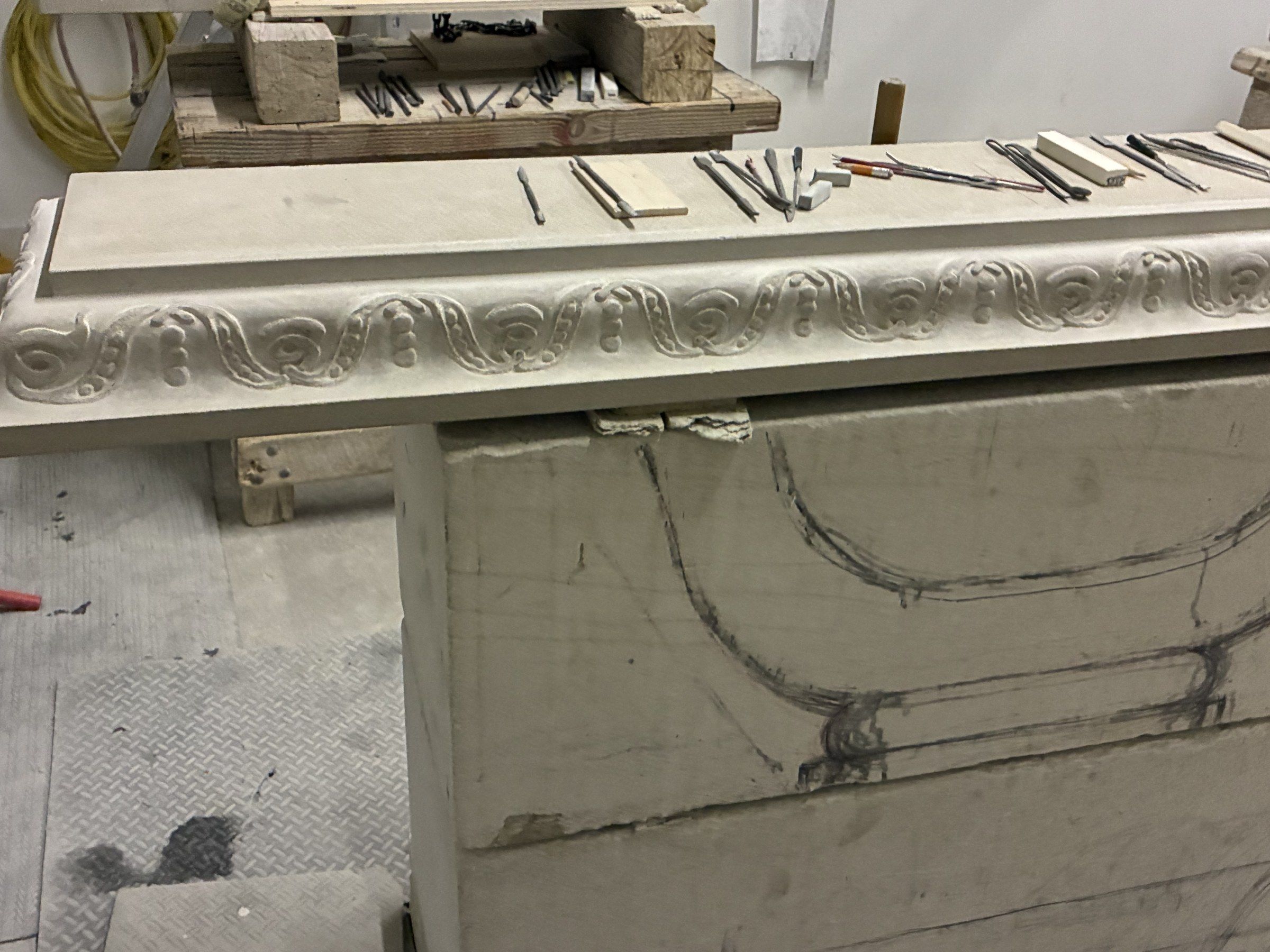 September 2025: the mantel shelf, its edge carved with a running scroll band, with carving tools laid along the top.
